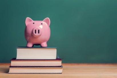 Piggy bank on top of books with chalkboard, cost of educatio